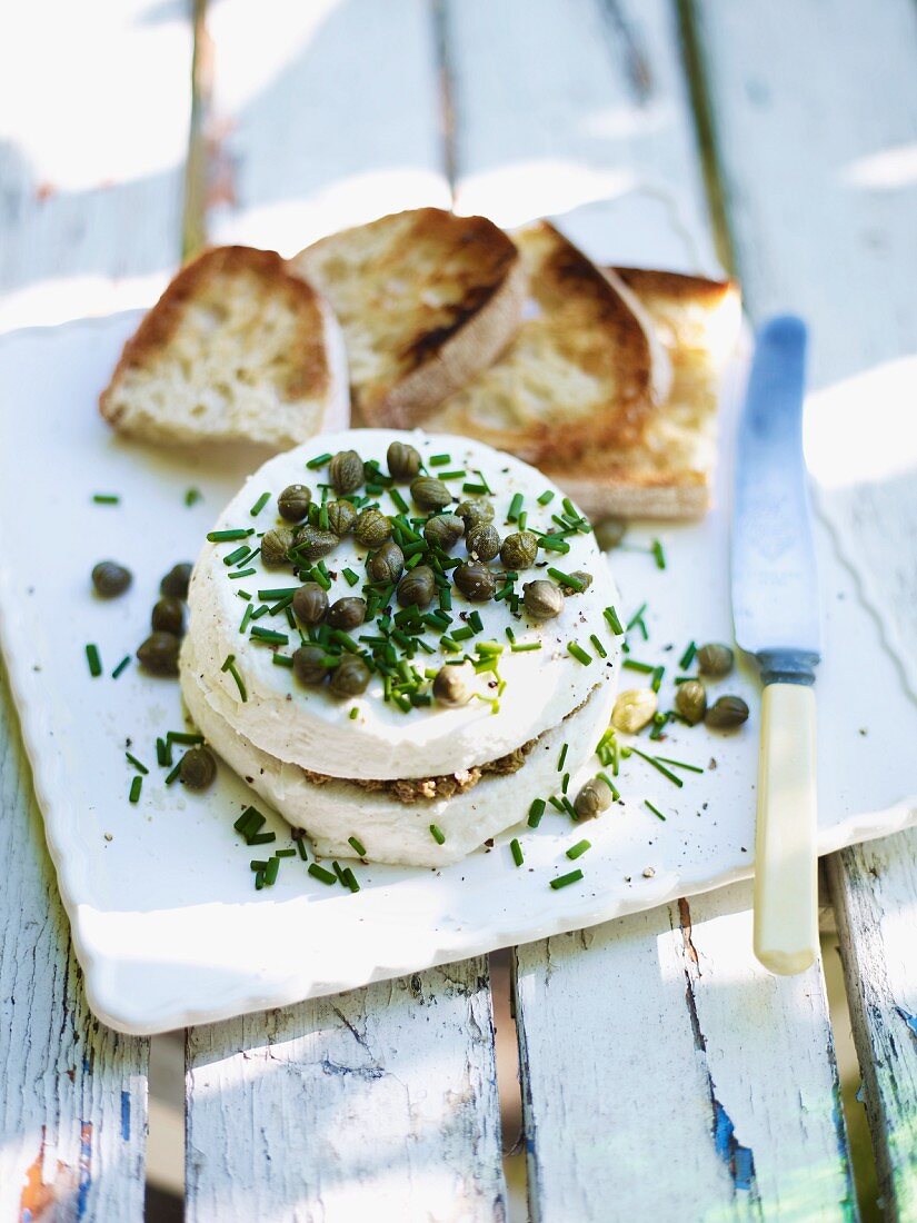 Ziegenkäse mit Tapenade gefüllt und mit Kapern und Schnittlauchröllchen bedeckt