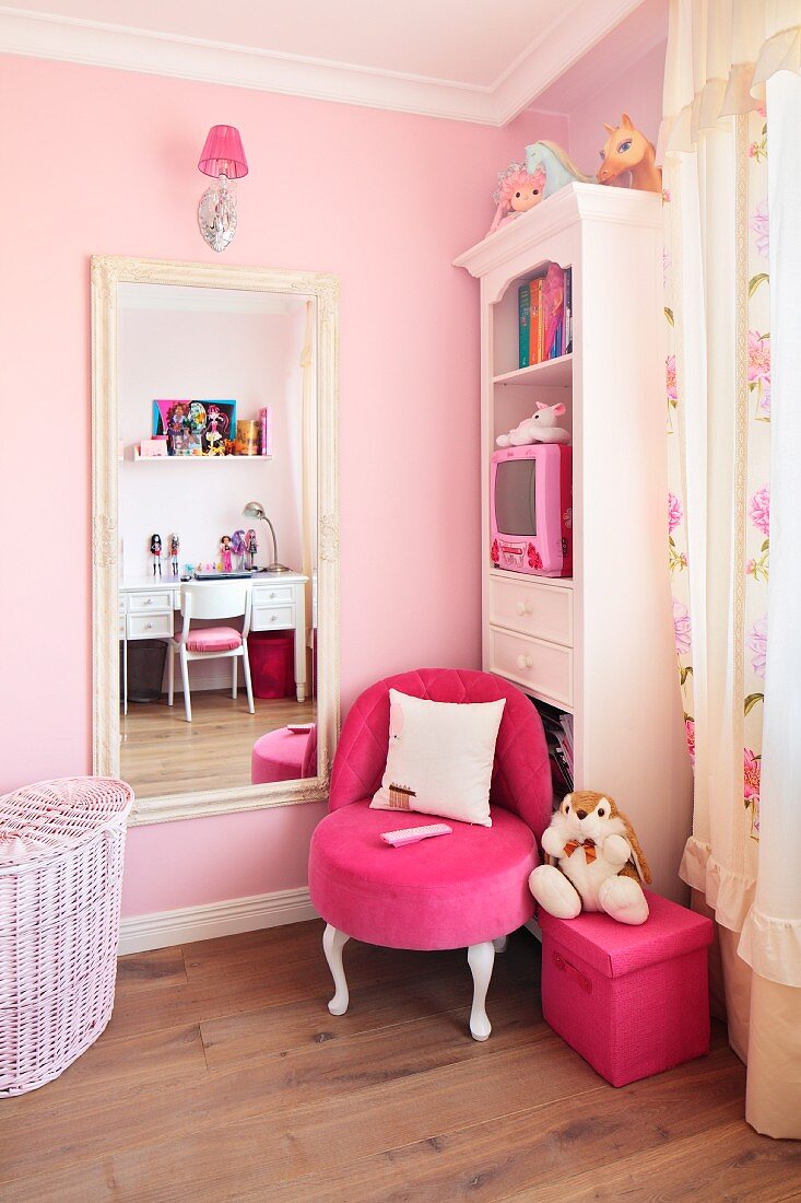 White antique style furniture and a neon pink upholstered chair against a pale pink painted wall in a little girl's bedroom