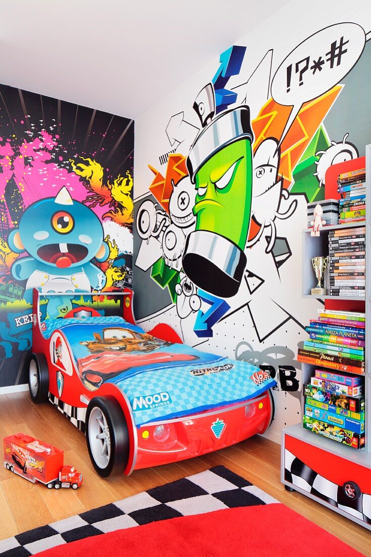 A children's room with a bright graffiti mural on the wall and a racing car bed