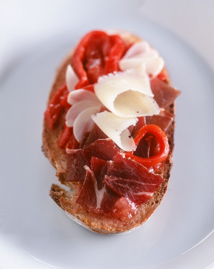 A slice of toasted bread topped with pata negra and manchego cheese