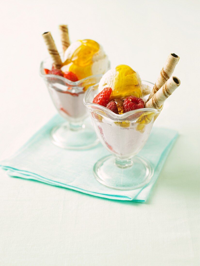 Fruity ice cream sundaes with maple syrup and wafer rolls