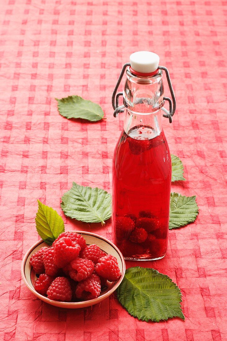 Eine Flasche Himbeeressig und frische Himbeeren