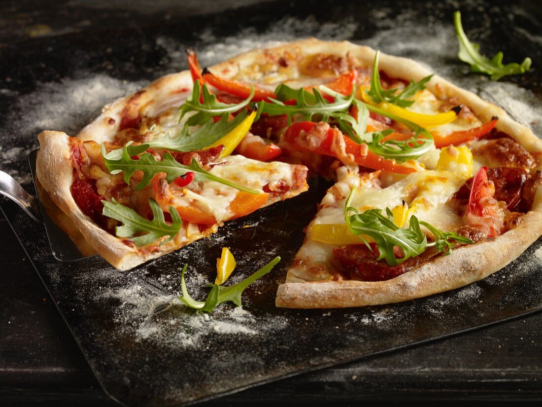 A pepper, rocket and peperoni pizza on an old baking try