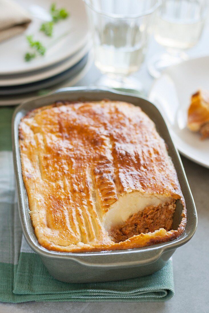 Empadão (minced beef and mashed potato bake, Portugal) in a baking dish with one portion removed