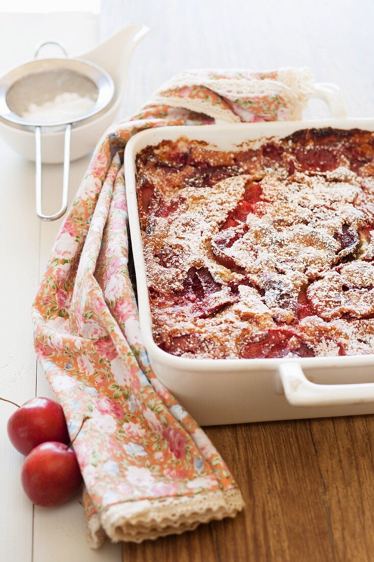 Freshly baked clafoutis with plums in a baking dish