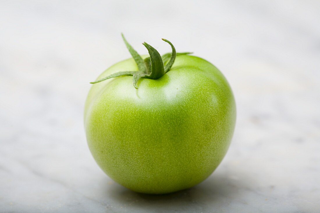 Eine grüne Tomate auf Marmorplatte