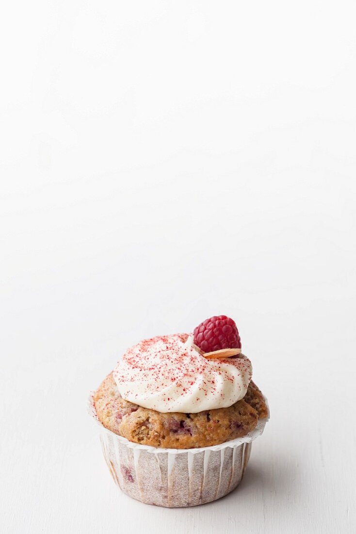 A raspberry and almond muffin topped with buttercream and decorated with dried raspberry powder