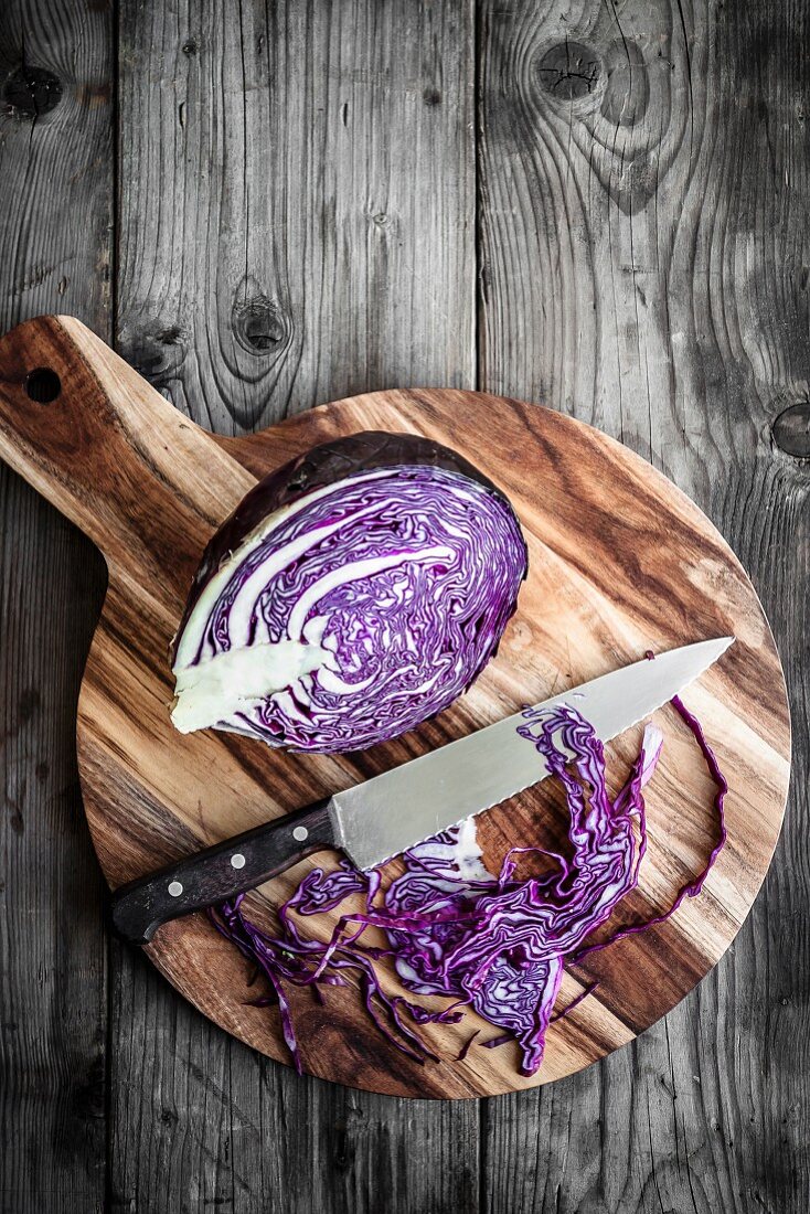 Sliced red cabbage on a chopping board with a knife