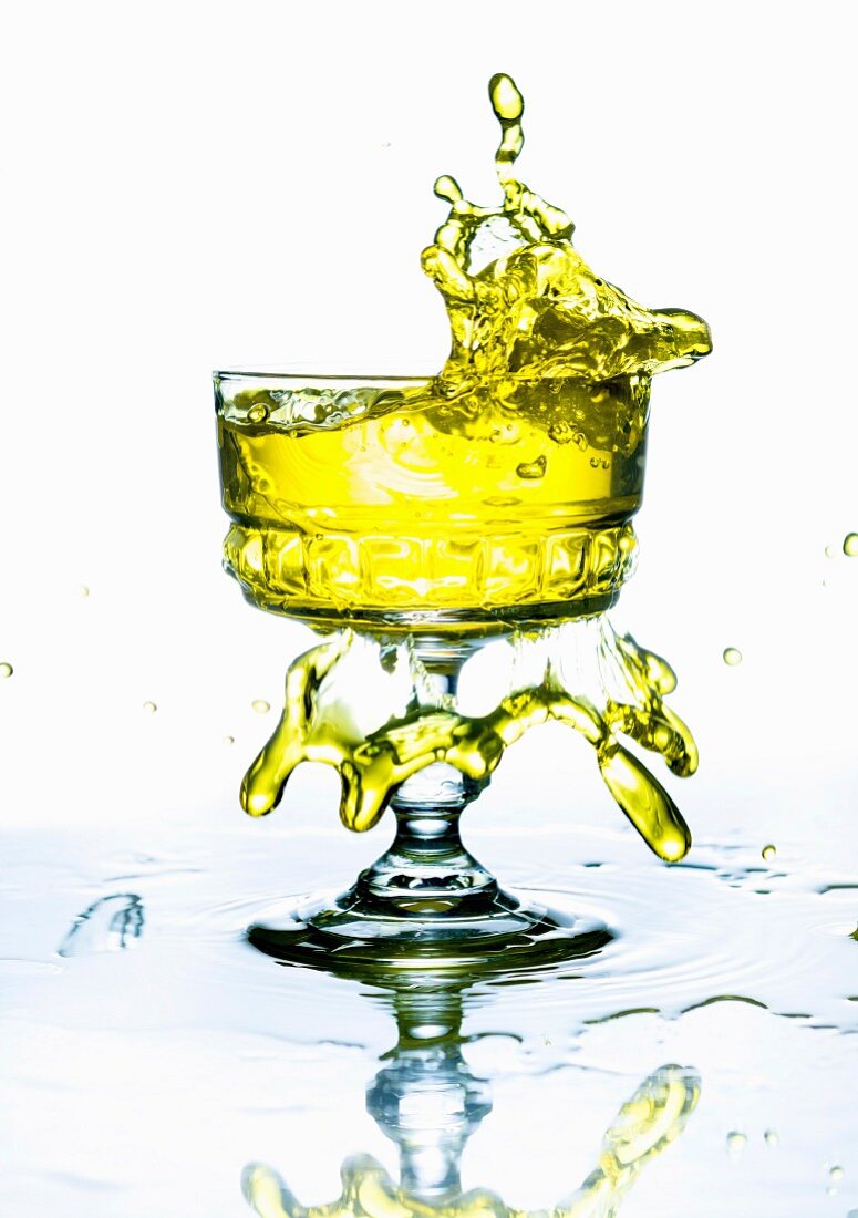 A yellow drink splashing from a glass
