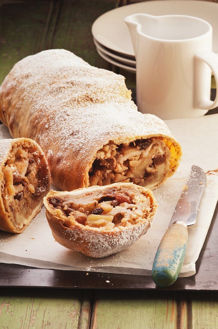 Apfelstrudel mit Rosinen und Puderzucker, angeschnitten