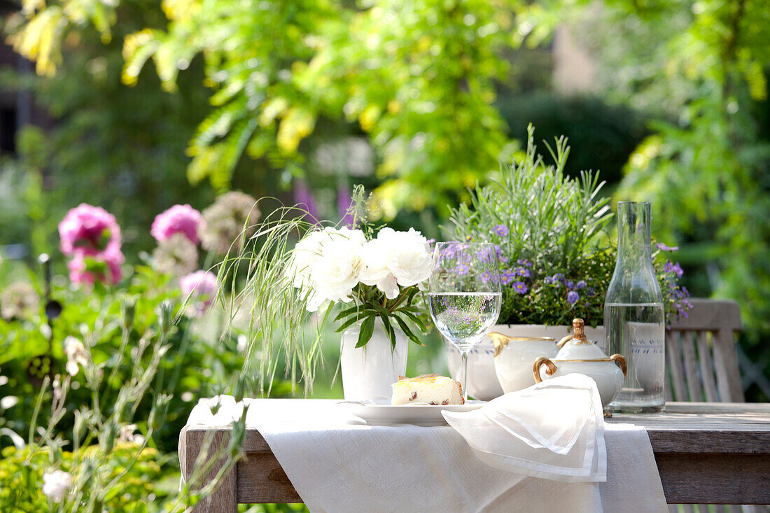 Slice of cake, a glass of water and a sugar pot on a garden table