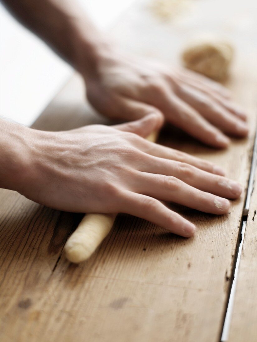 Raw pasta dough being rolled into a sausage