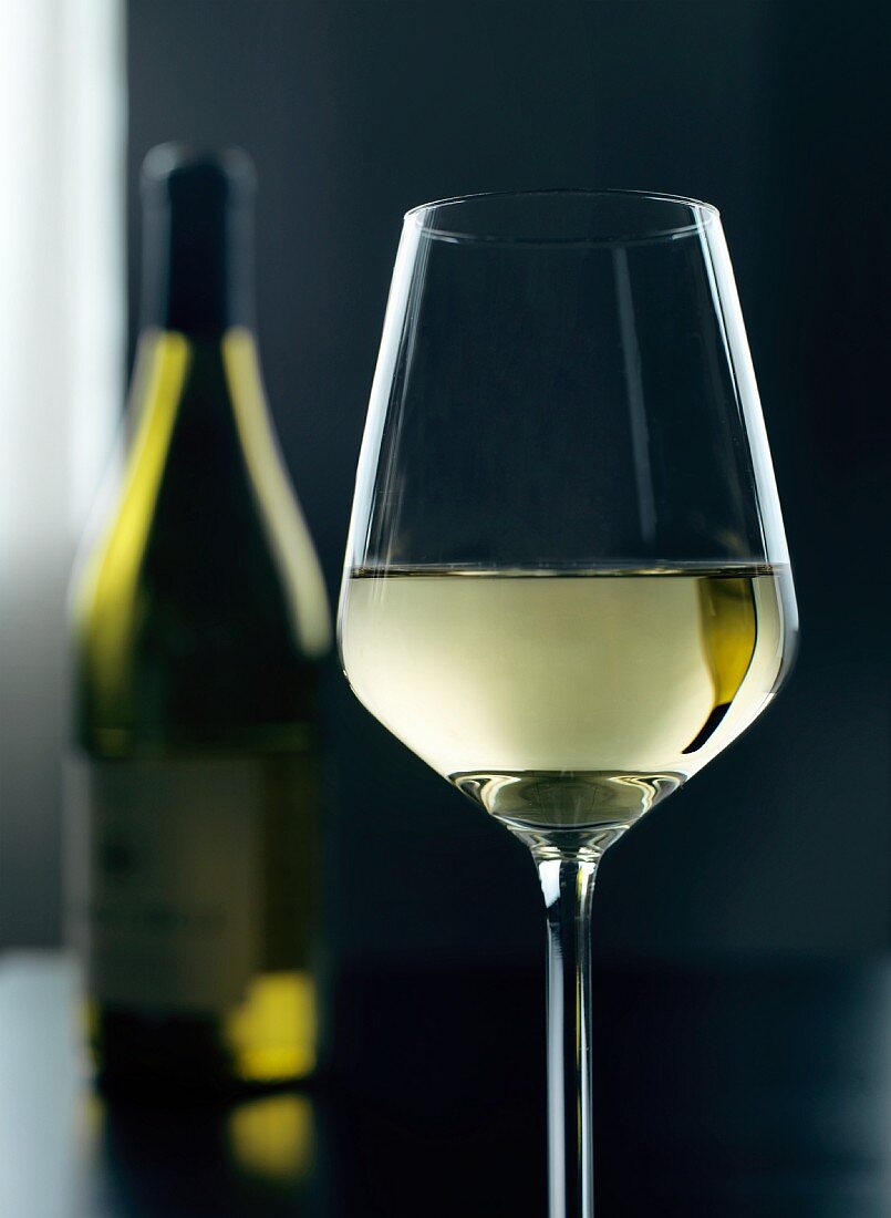 A glass and a bottle of white wine