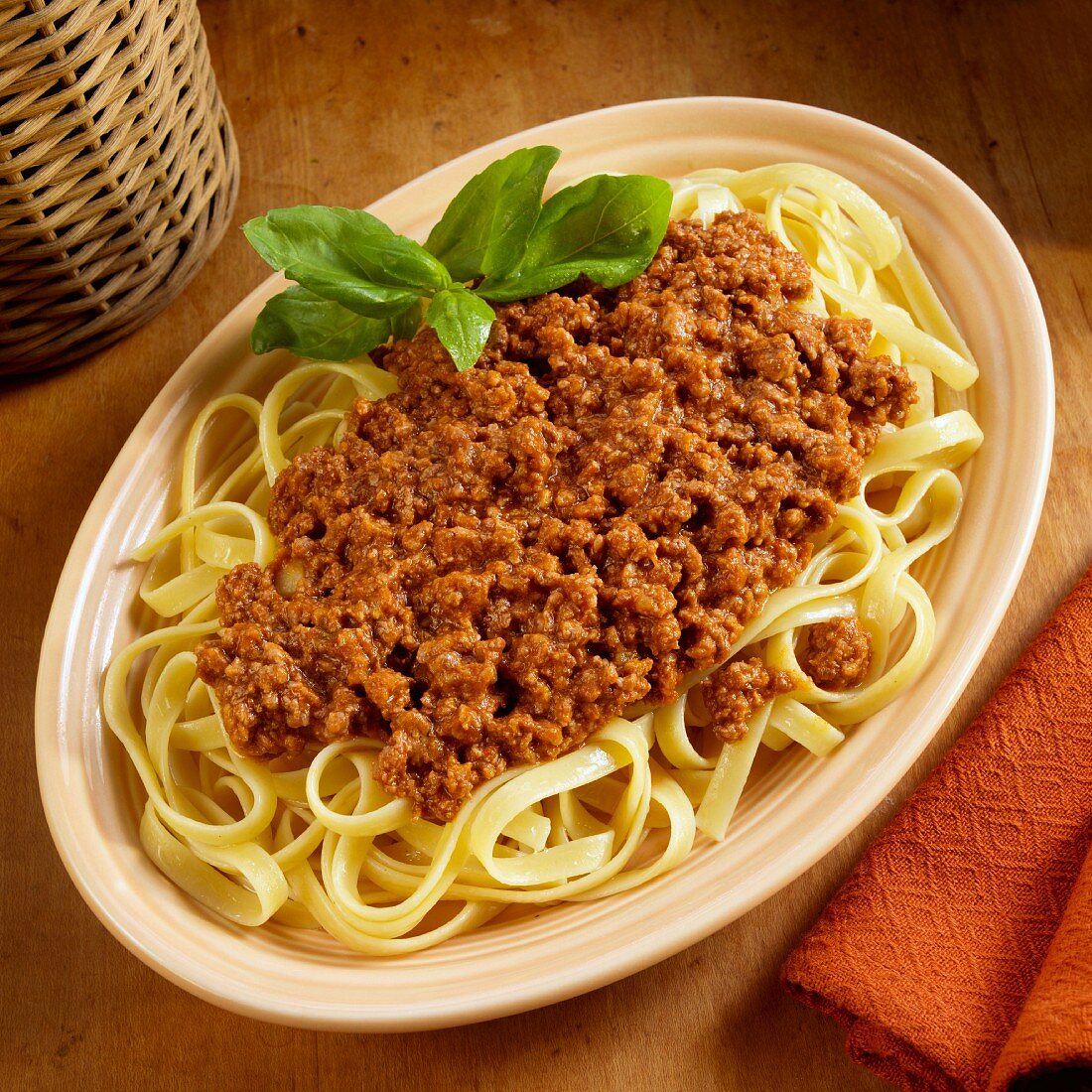 Fetuccini pasta with a meat sauce garnished with basil