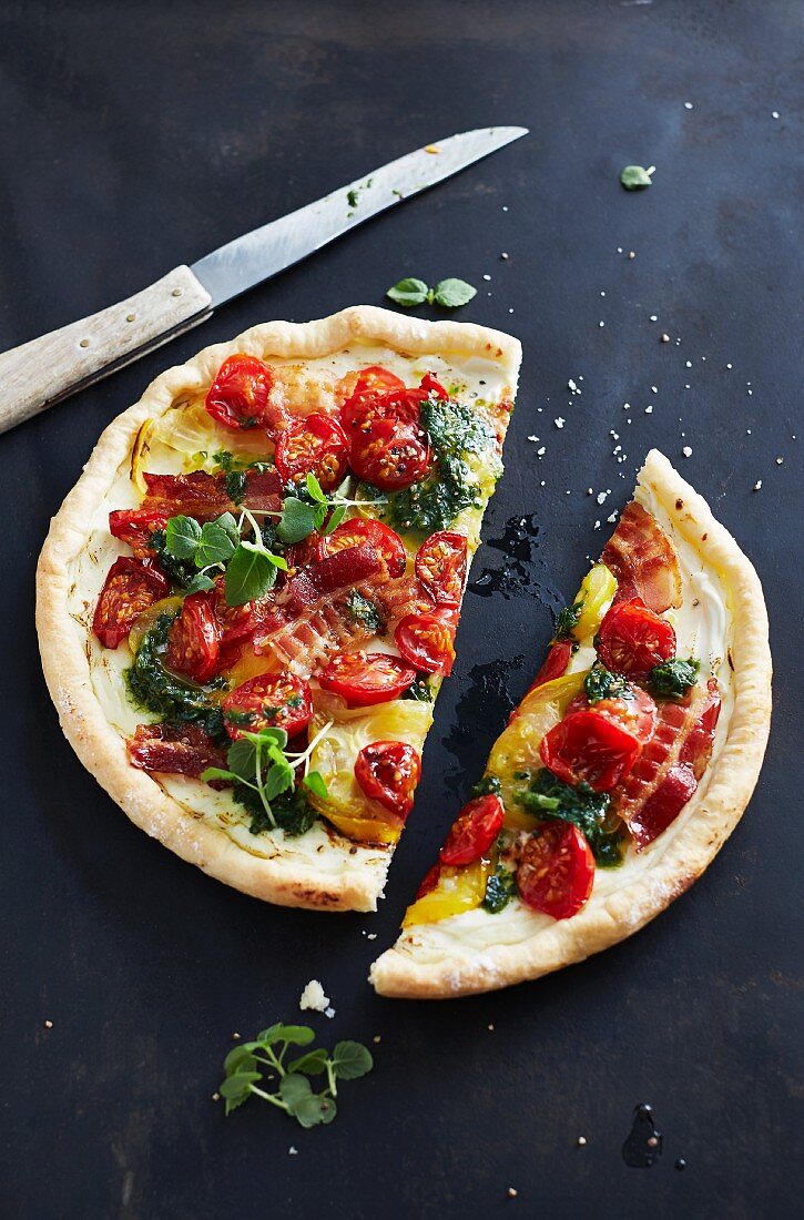 Pizza with pesto, tomatoes, bacon and herbs