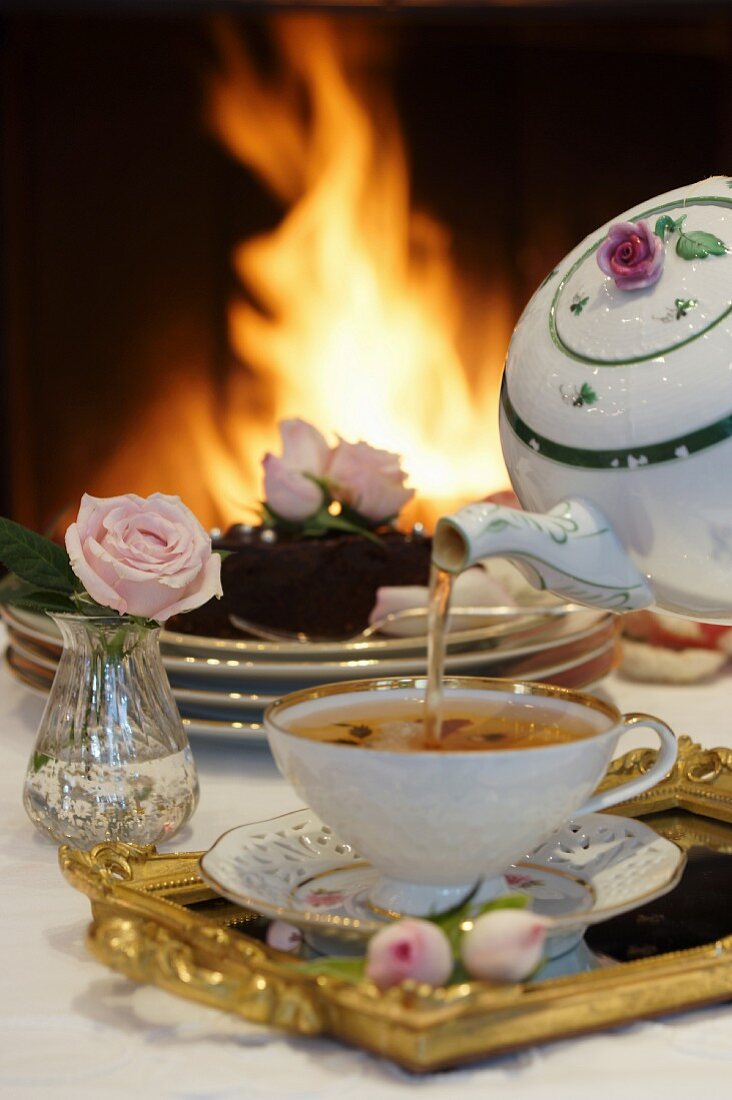 Tea and chocolate cake in front of an open fire