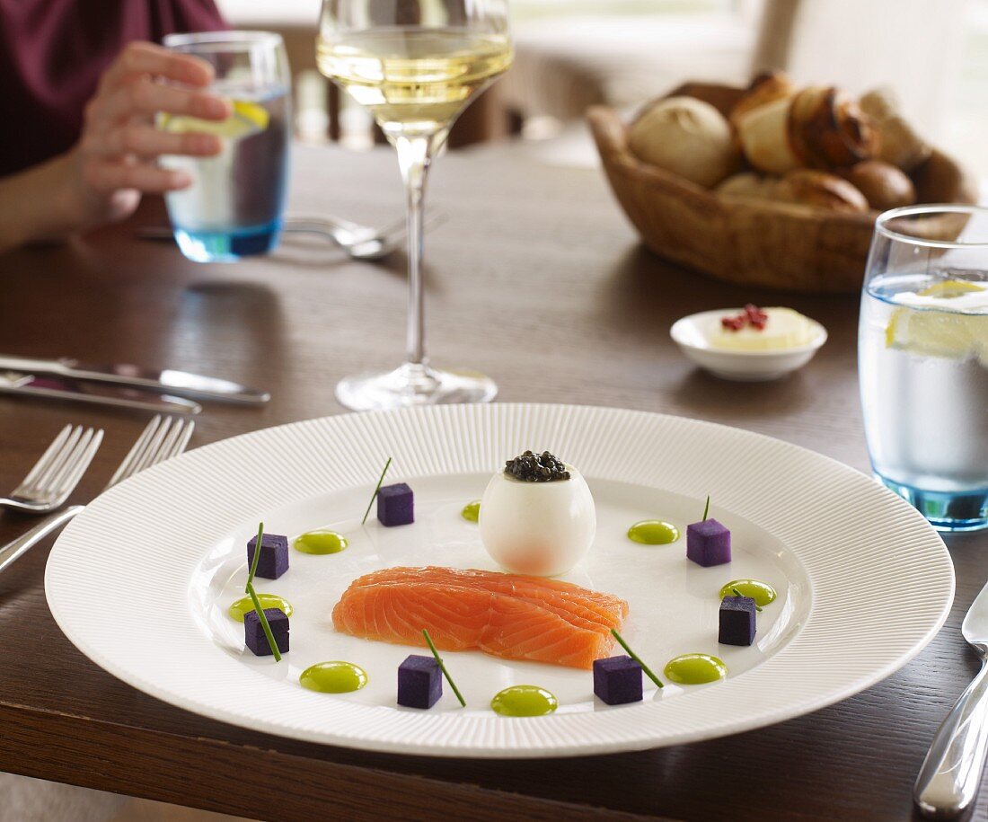 Smoked salmon with egg, caviar and purple potatoes on a table in a restaurant