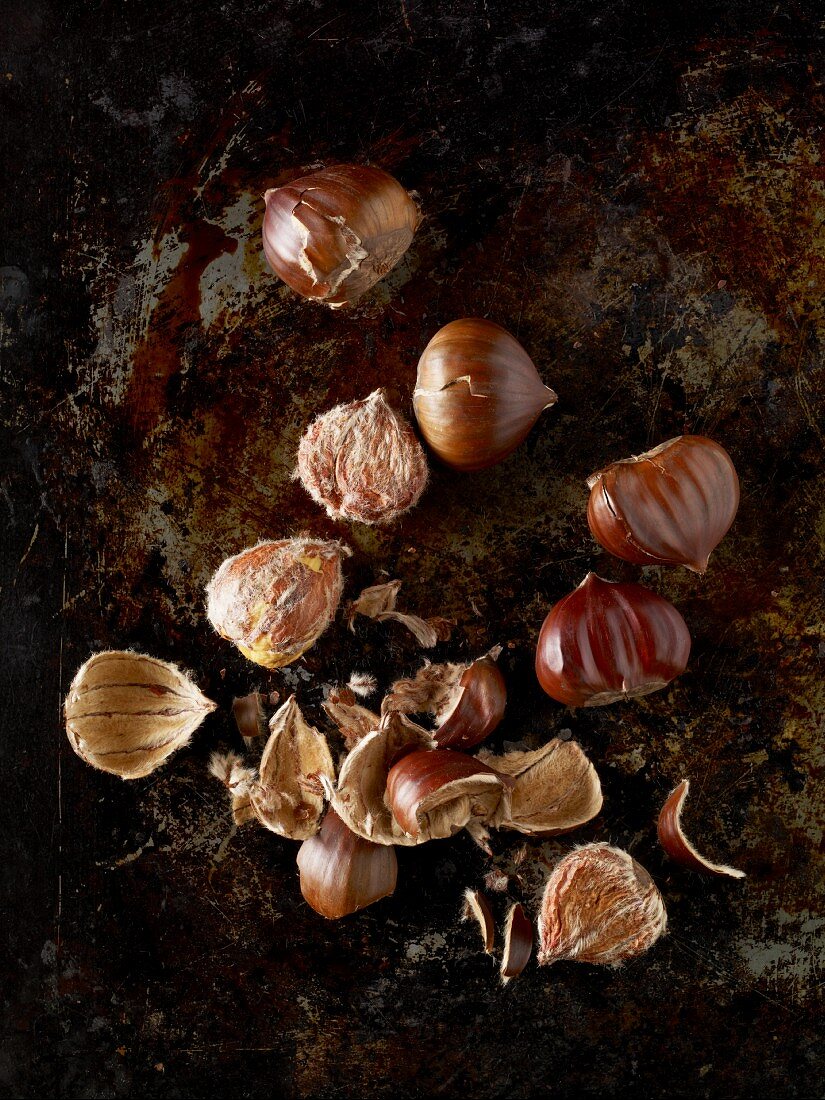 Roast chestnuts, some shelled, on a baking tray