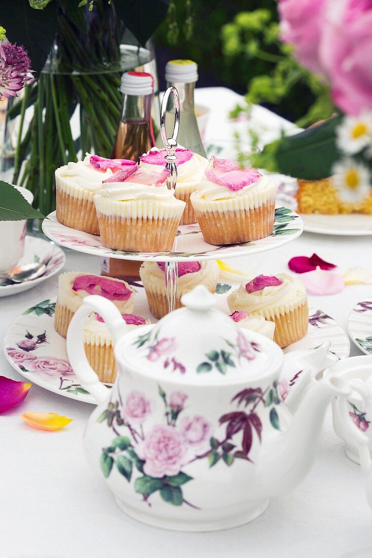 Rosenblüten-Cupcakes auf gedecktem Teetisch