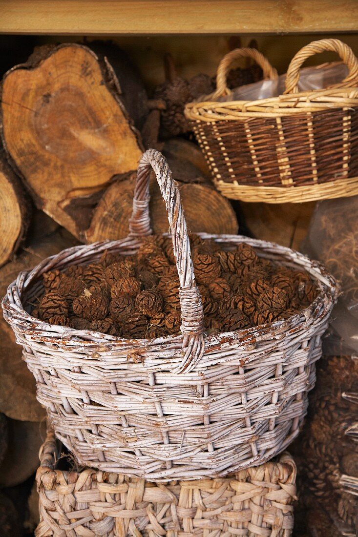A rustic wicker basket filled with pine cones in front of a wood shed