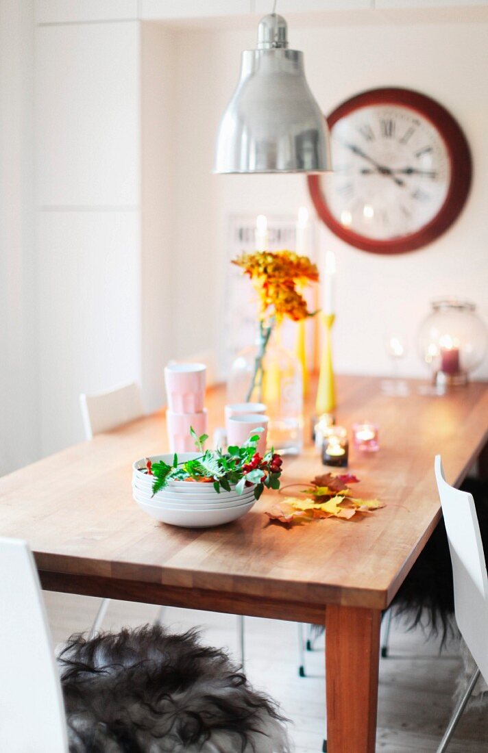 Autumnal arrangement and tealights on untreated wooden table