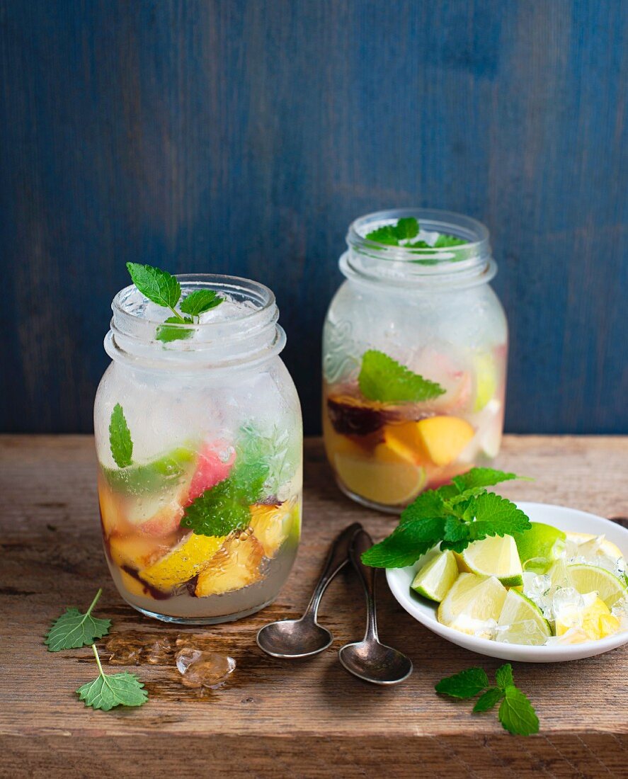 Homemade lemonade with fruit, ice cubes and lemon balm