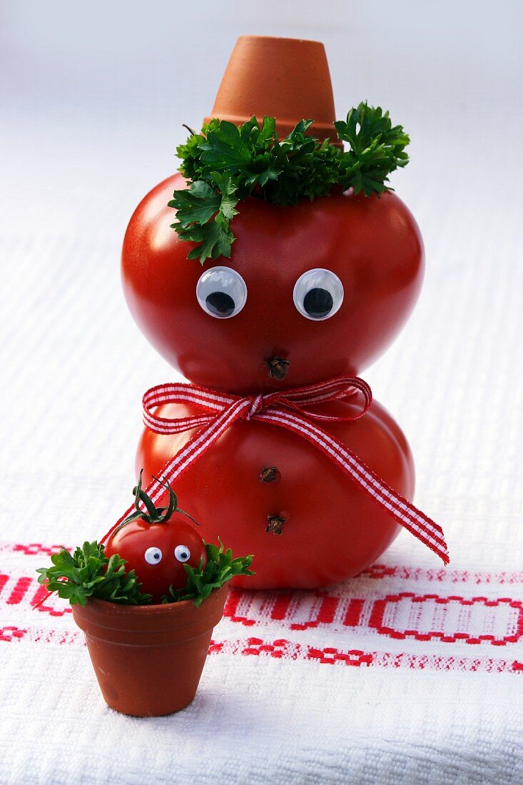 A tomato man with a face and a tomato baby in a flowerpot