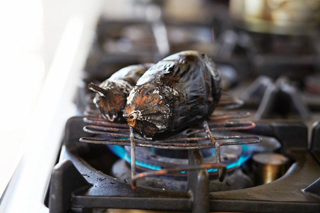 Charred aubergine on a gas stove