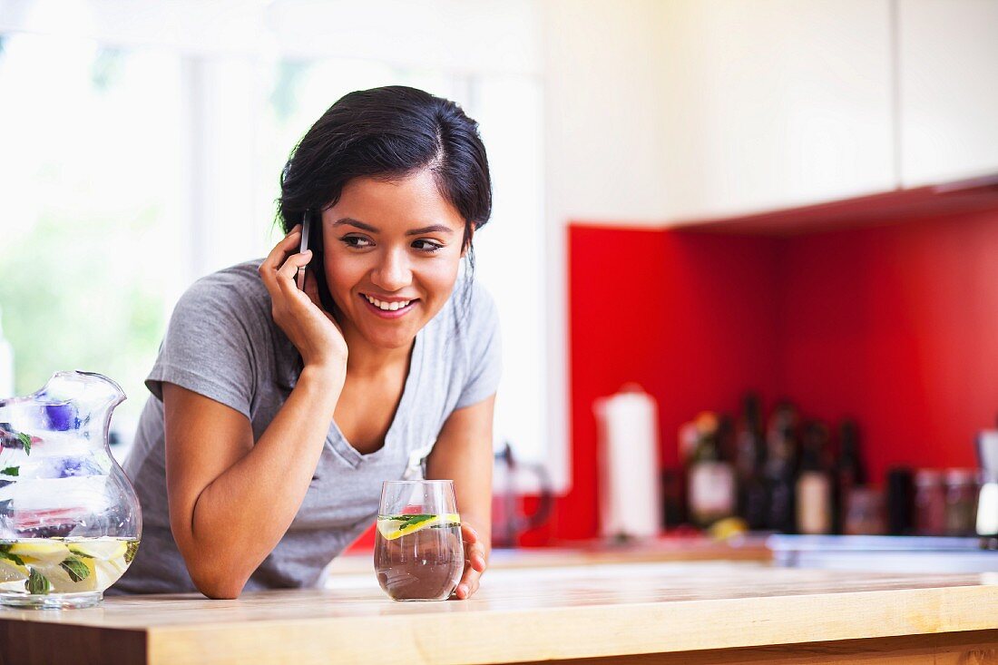 A young woman using a mobile phone in a kitchen