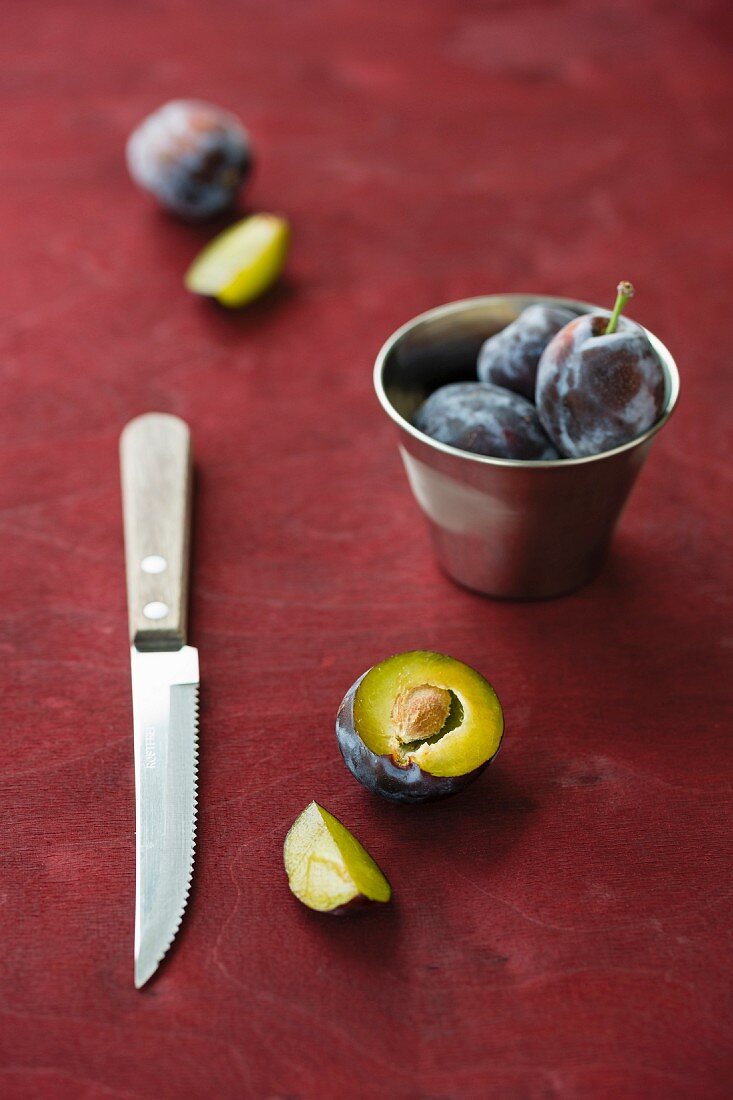 Damsons with a metal cup and a knife