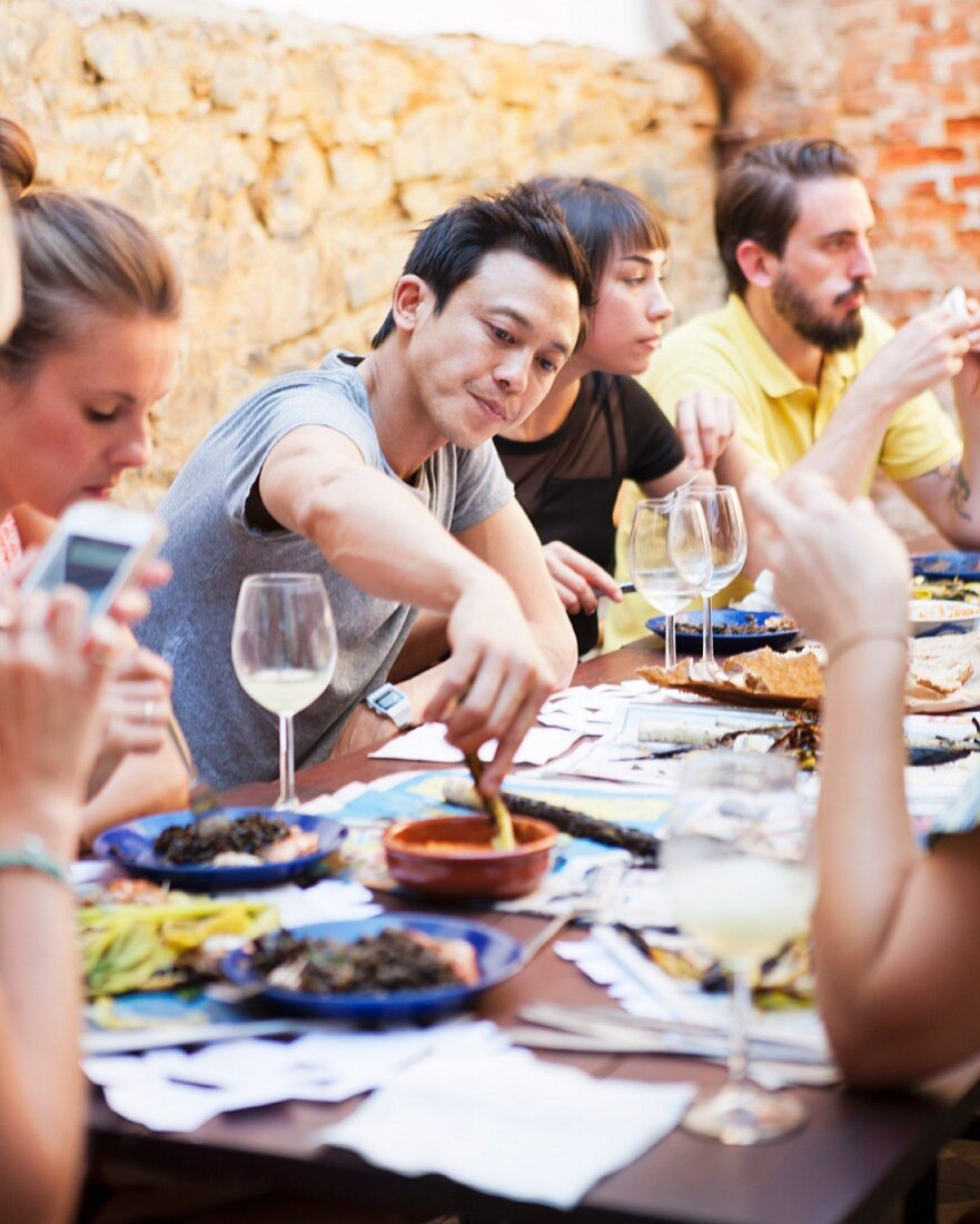 Mann asiatischer Herkunf dippt Lauch in Romesco