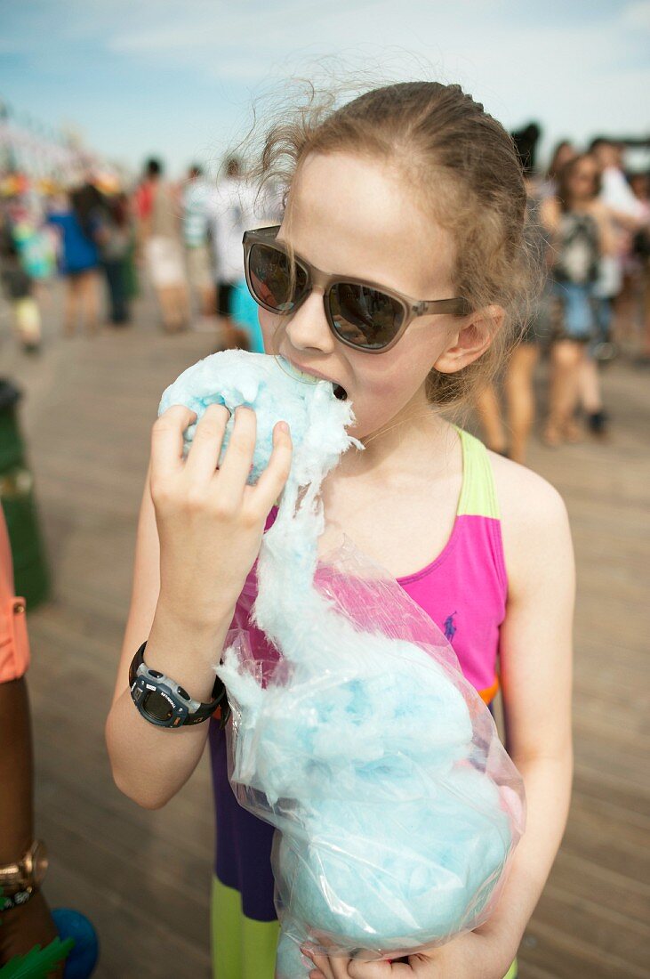 Mädchen isst Zuckerwatte auf einem Jahrmarkt