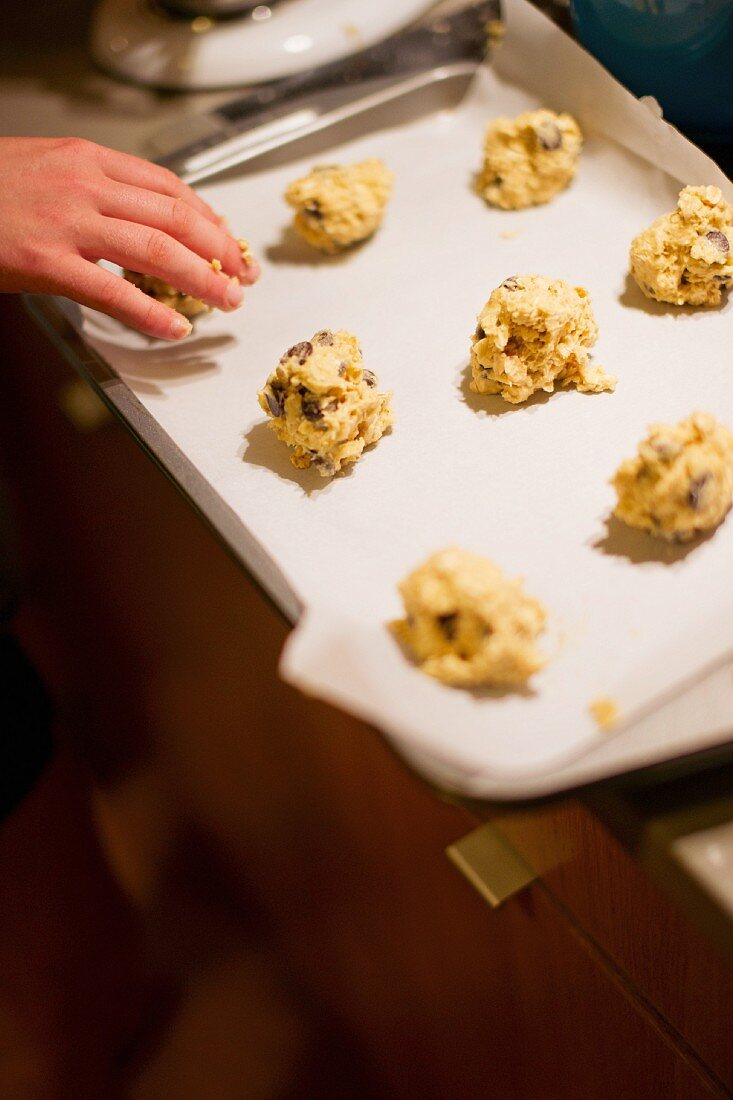 Balls of cookie dough being placed on baking tray