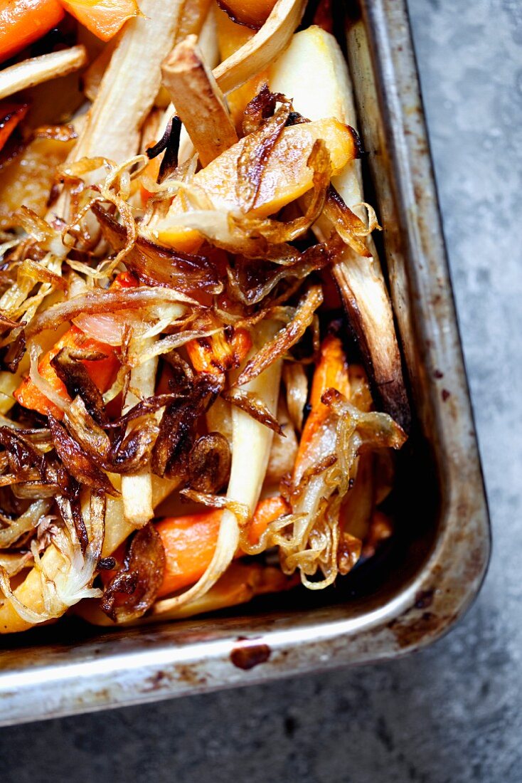 Rabbit with root vegetables and onions in a baking tray