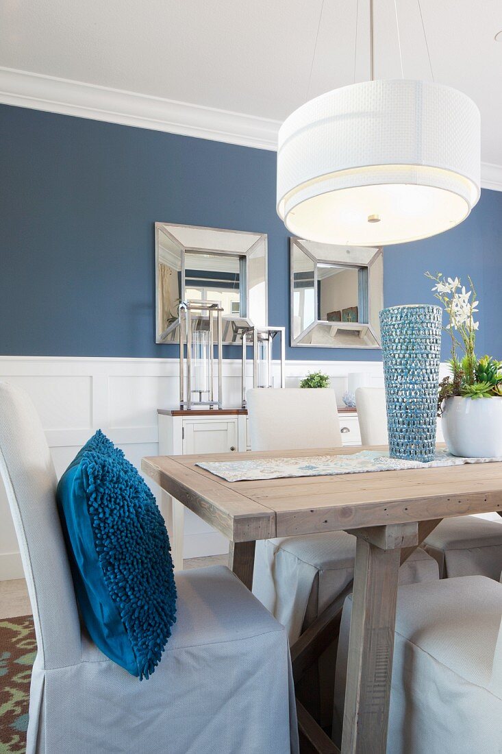 Esszimmer in blau-weiss mit Esstisch aus Holz, Hussenstühlen & Pendelleuchte