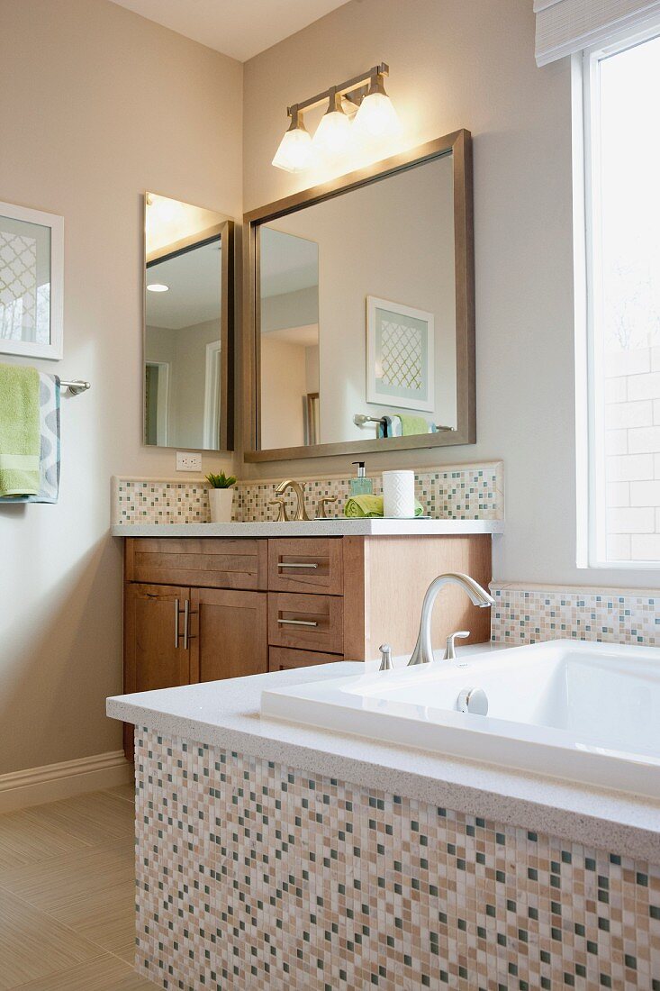 Bathtub, cabinet and mirror in bathroom