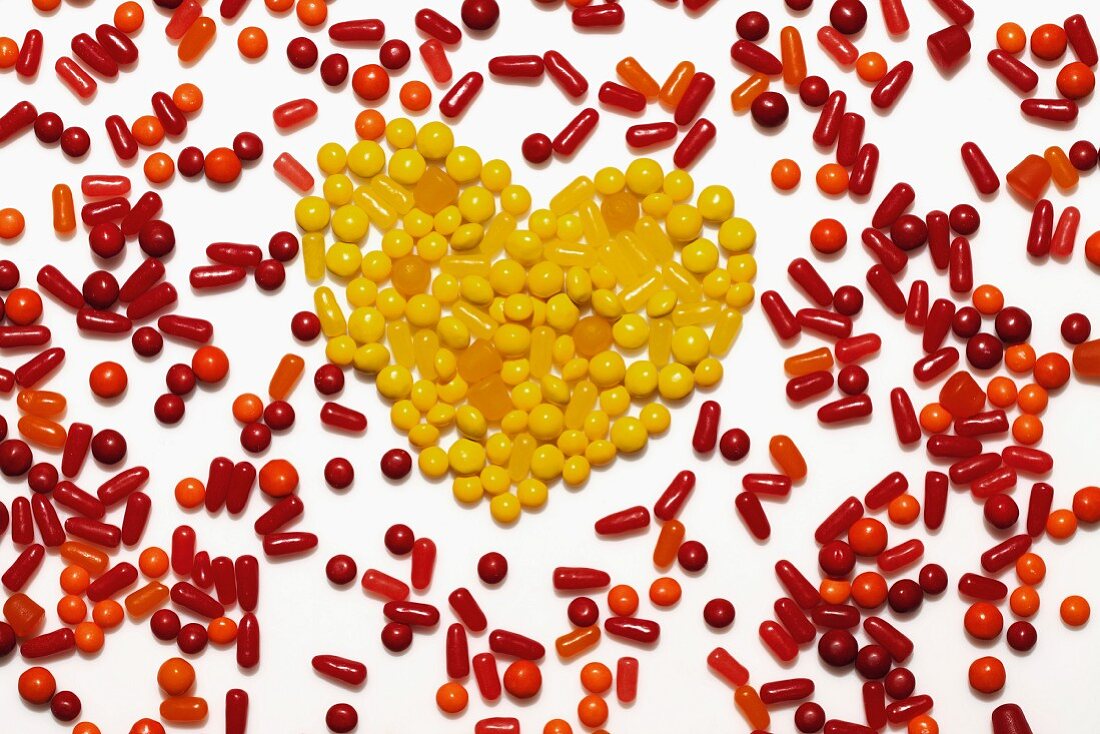 A heart made from yellow bonbons surrounded by red and orange bonbons