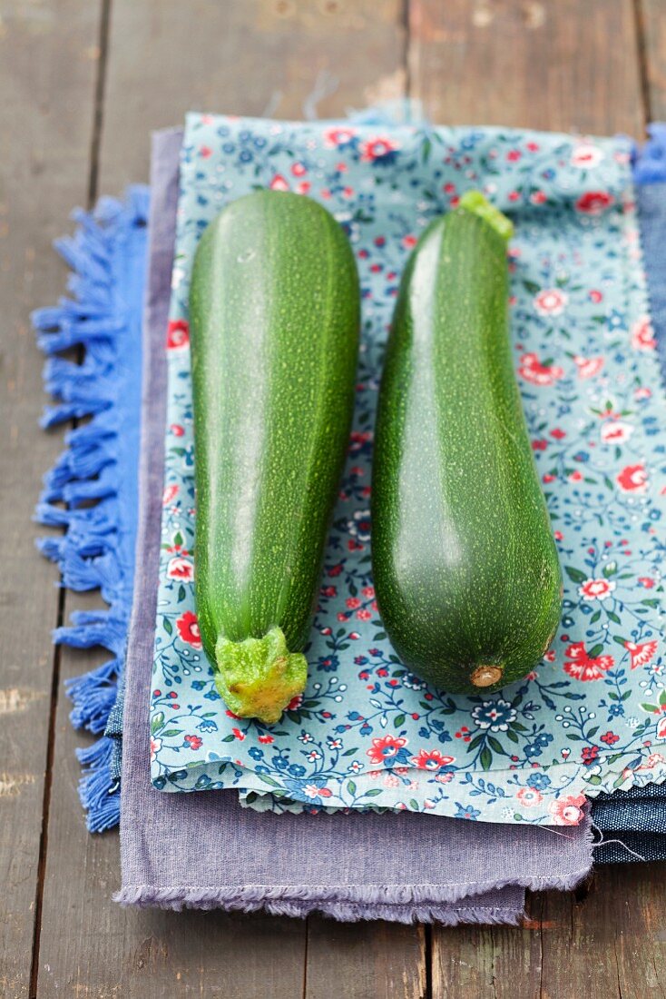 Two courgettes on a floral-patterned cloth