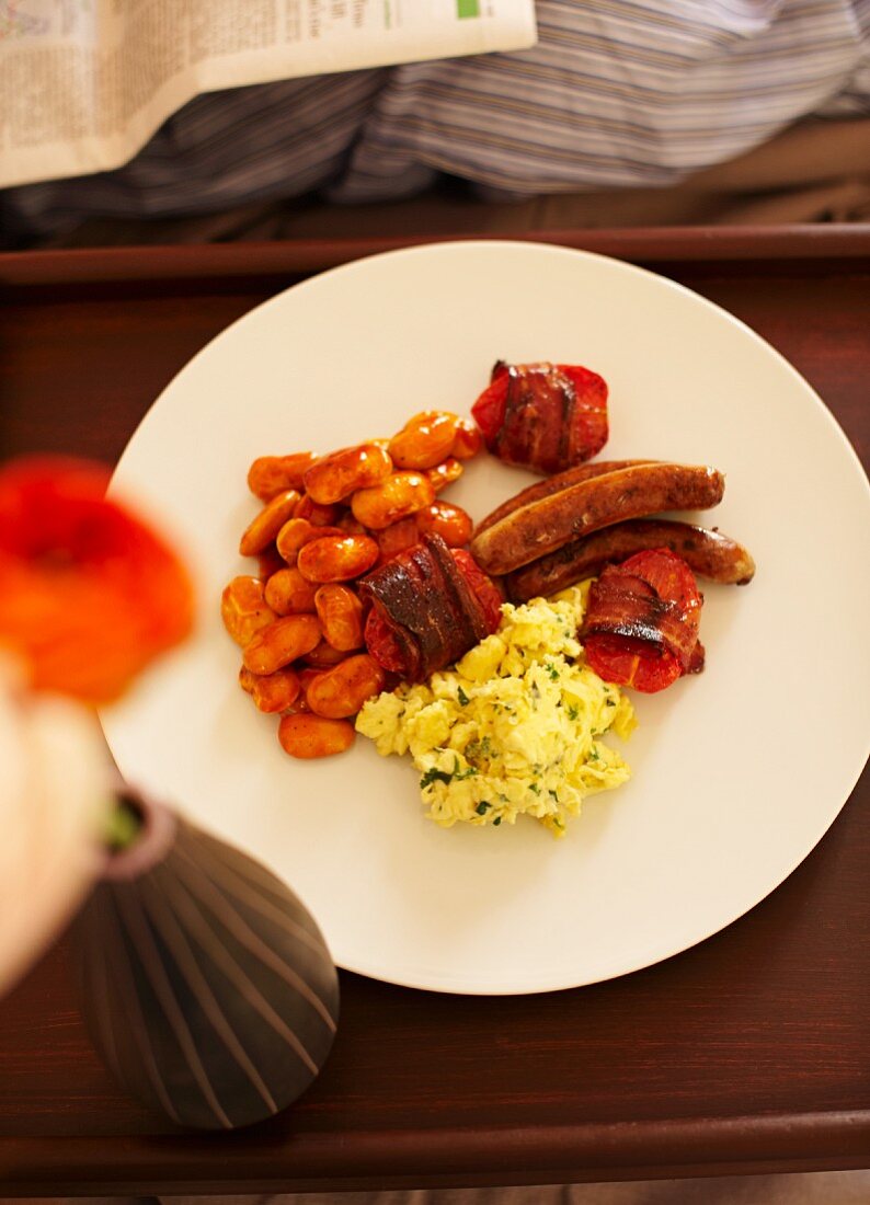 Englisches Frühstück mit Rührei, Baked Beans, Tomaten, Bacon und Bratwürstchen