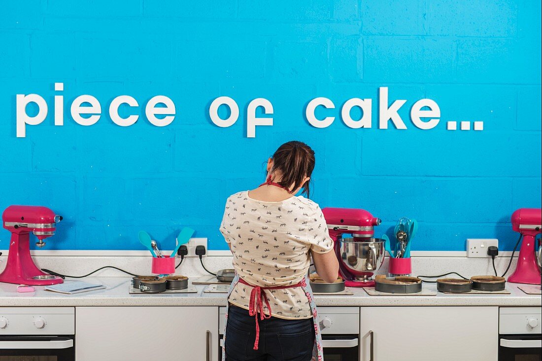 A young woman, seen from behind, in a bakery with various mixers