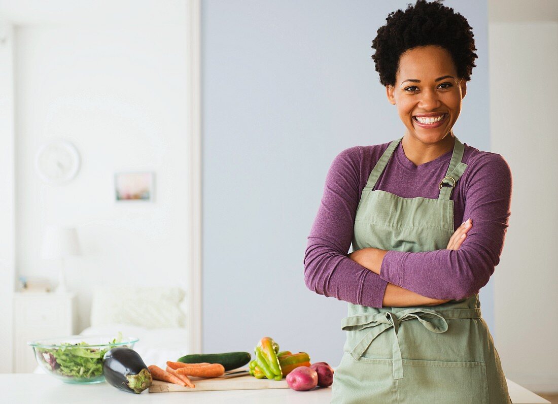 A young black woman in a kitchen with vegetables