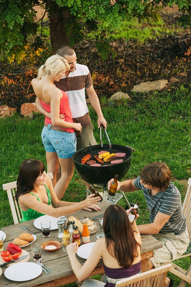 Young people barbecuing and eating in a garden