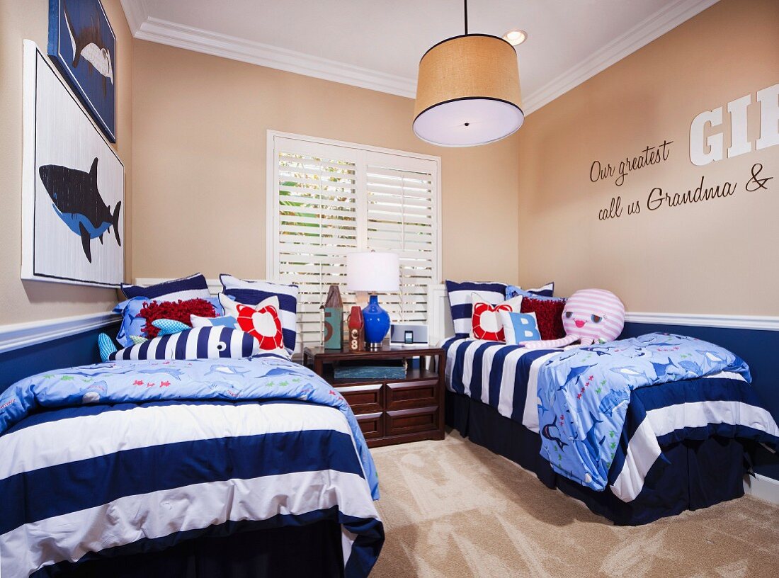 Zwei Einzelbetten mit Bettwäsche im Marine-Design in Kinderzimmer mit beigen Wänden & Teppichboden