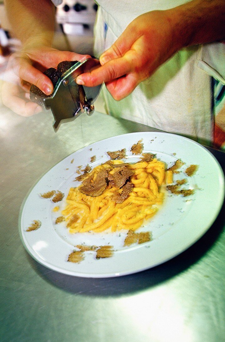 A chef grating a truffle onto saffron pasta