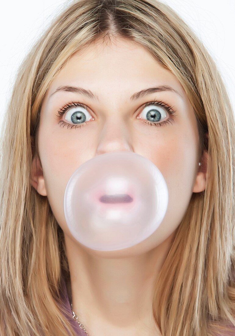 A young woman blowing a large bubblegum bubble