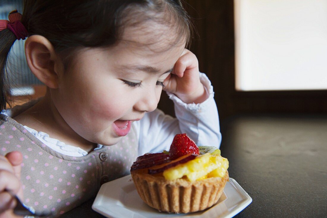 A little girl with a fruit tartlet