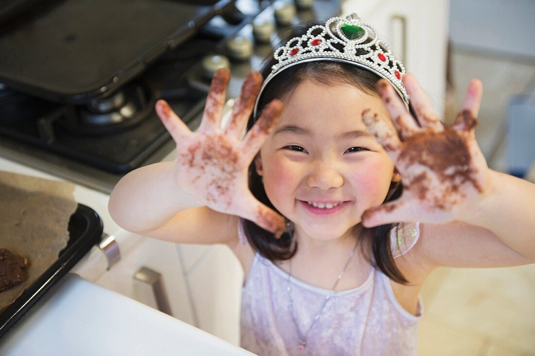 A little girl showing her chocolate-smeared hands