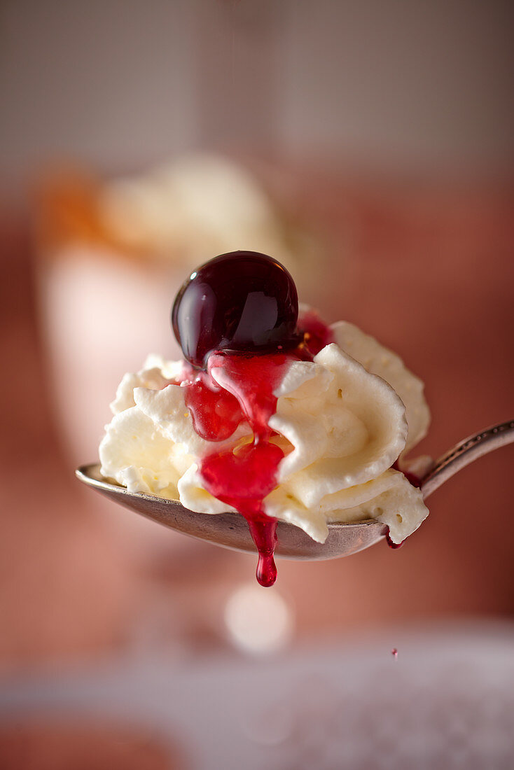 A spoonful of cream topped with an amarena cherry