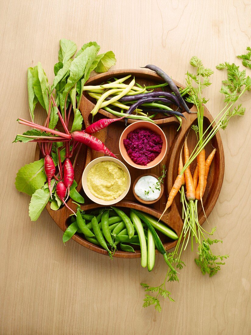 Fresh garden vegetables with dips on a wooden platter