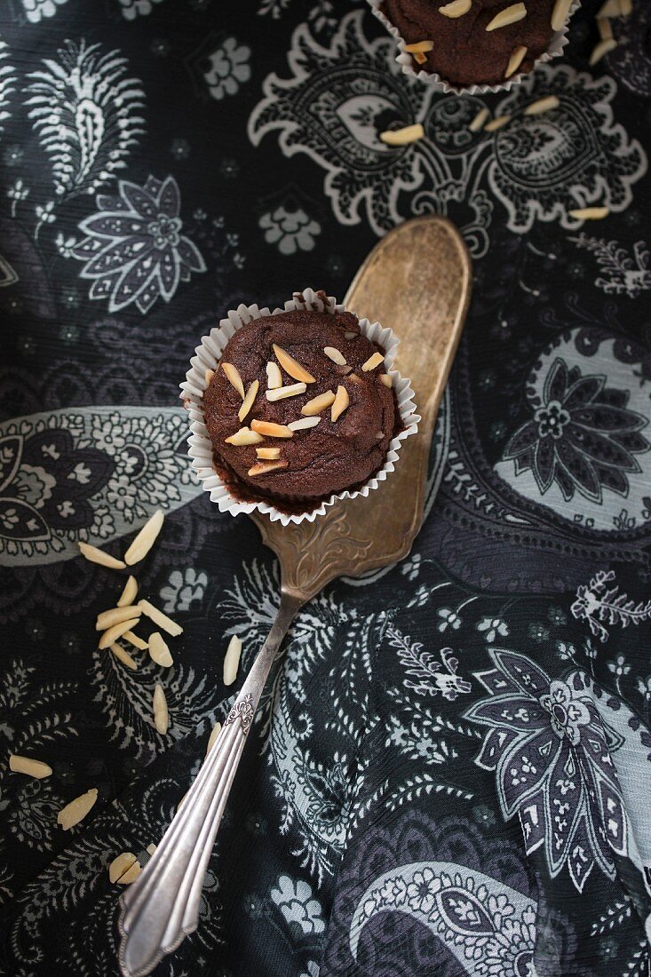 A chocolate muffin decorated with slivered almonds on a cake slice